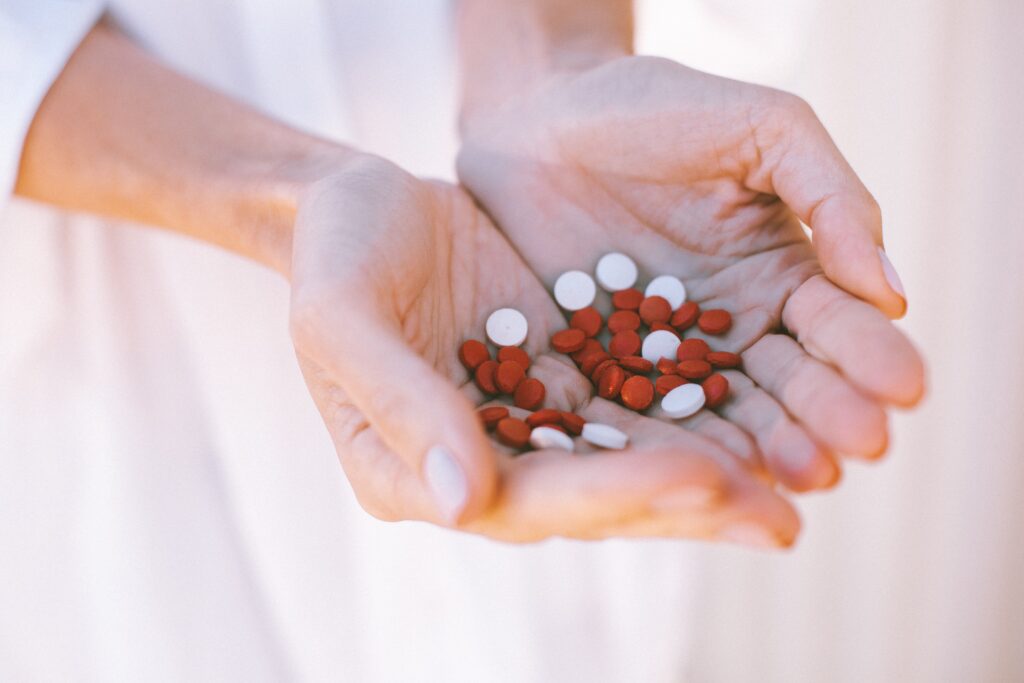 white and red pill medication pills in persons hand