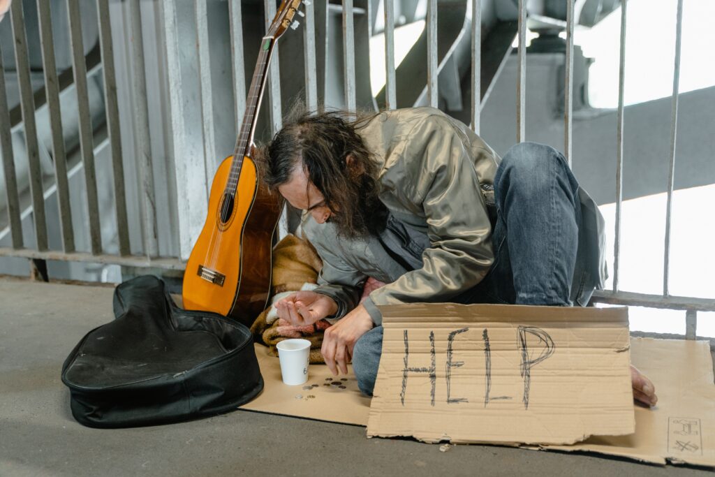 homeless man on the floor with help sign