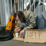 homeless man on the floor with help sign
